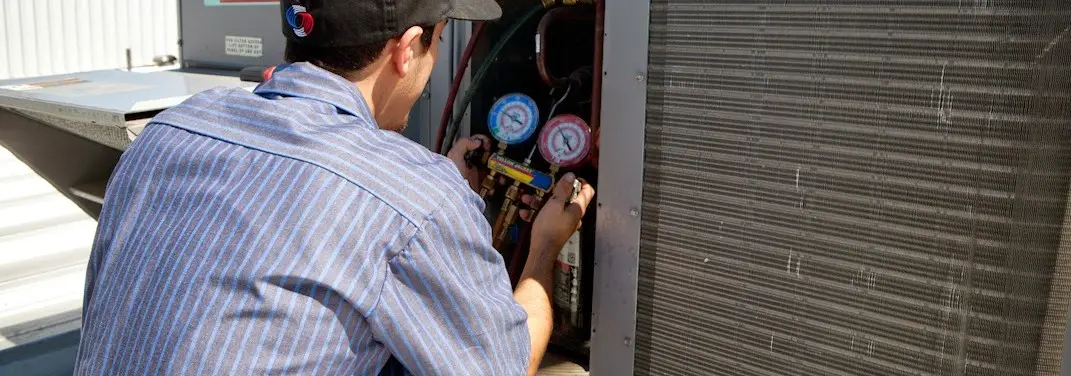 HVAC technician servicing a condenser unit in Madeira